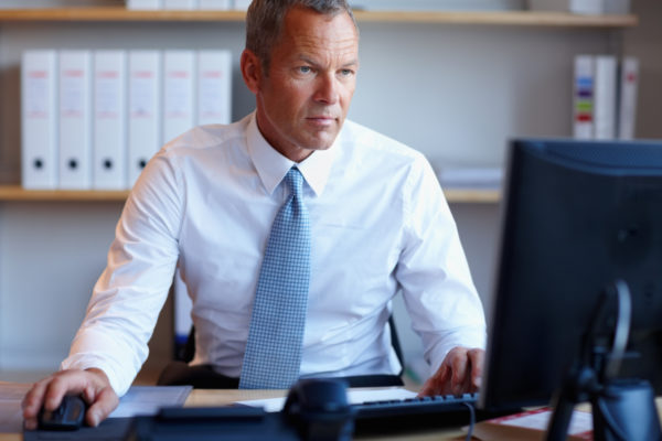 Serious mature business man working on a project using computer