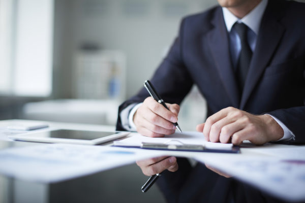 Close-up of male hands with pen over document